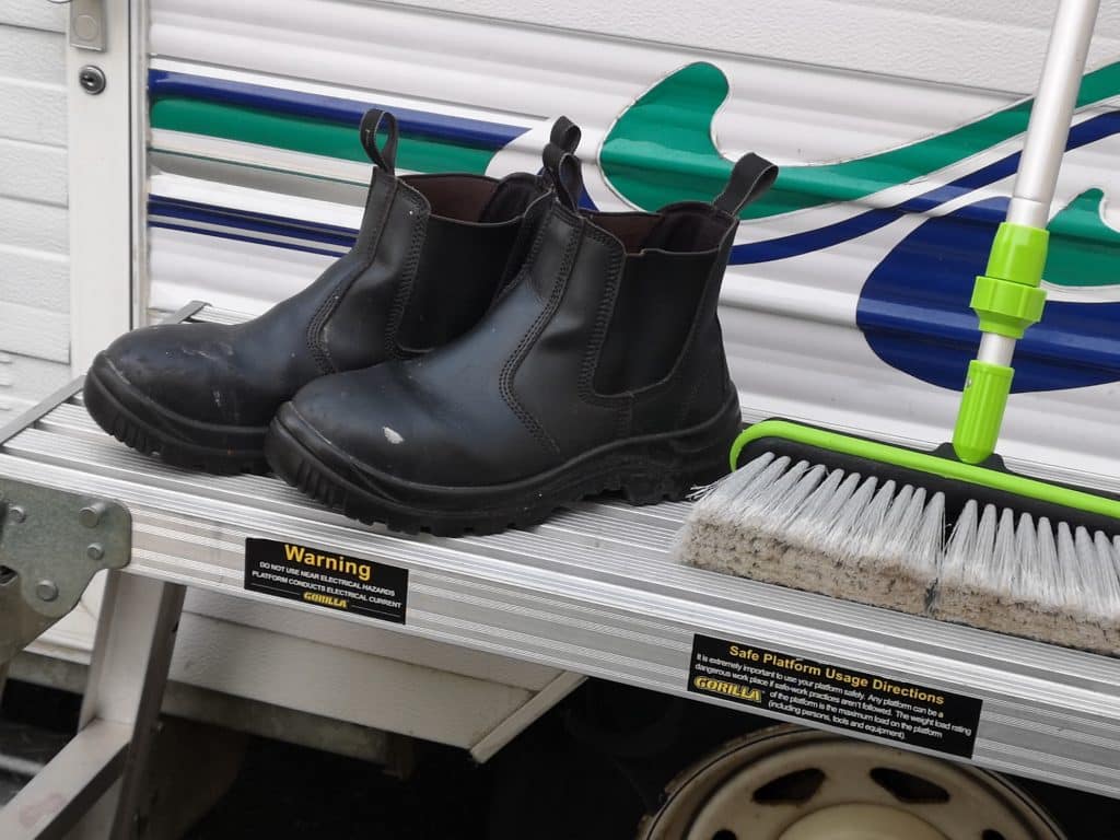 Trestle tables, boots and brush in front of a camper trailer 