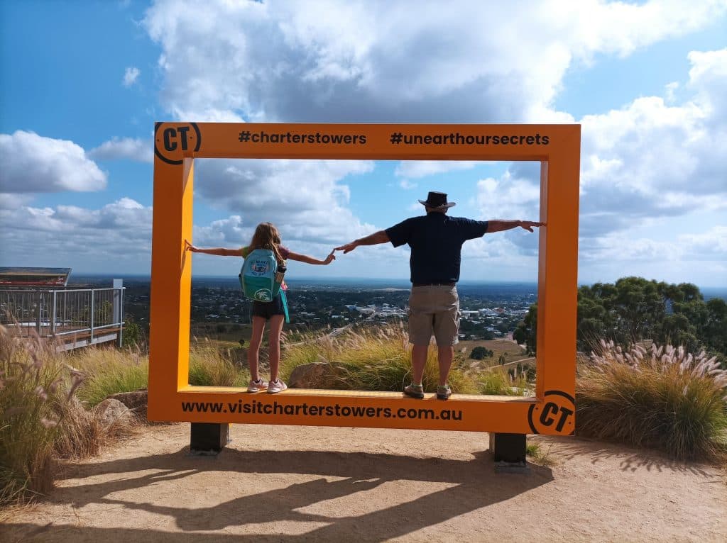 Grandfather and grandchild frame scenic Charter Towers vista during a camping adventure