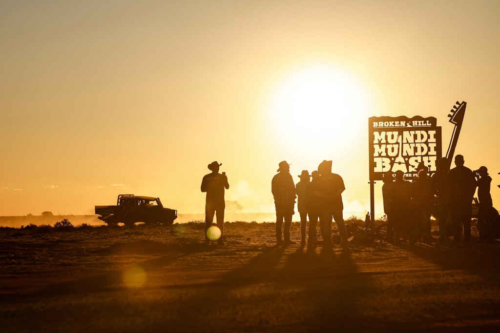 New INEOS Quartermaster owners congregate at the iconic Mundi Mundi Bash sign at sunset with the Quartermaster in the background